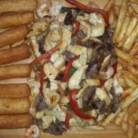 Parilla Suprema · Sauteed pepper steak, chicken and shrimps over French fries and yuca.