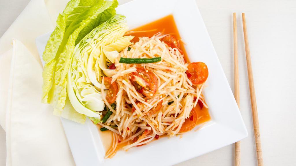 Green Papaya Salad (Som Tum) · Freshly shredded green papaya prepared with tomatoes, house tamarind sauce, and served with lettuce and cabbage.