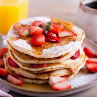 Strawberry Buttermilk Pancakes · Three perfectly fluffy strawberry pancakes served with a side of butter and syrup.