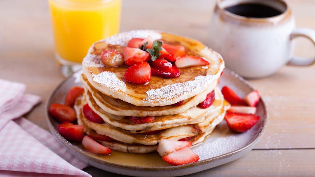 Strawberry Buttermilk Pancakes · Three perfectly fluffy strawberry pancakes served with a side of butter and syrup.