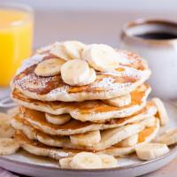 Banana Buttermilk Pancakes · Three perfectly fluffy banana pancakes served with a side of butter and syrup.