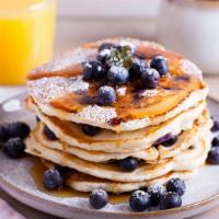 Blueberry Buttermilk Pancakes · Three perfectly fluffy blueberry pancakes served with a side of butter and syrup.