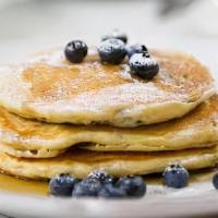 Blueberry Pancakes  · Three large blueberry pancakes served with side of maple syrup and butter.