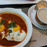 Shakshuka · Tomatoes, onions and bell-peppers sauce, topped with two eggs sunny-side up and fresh parsle...