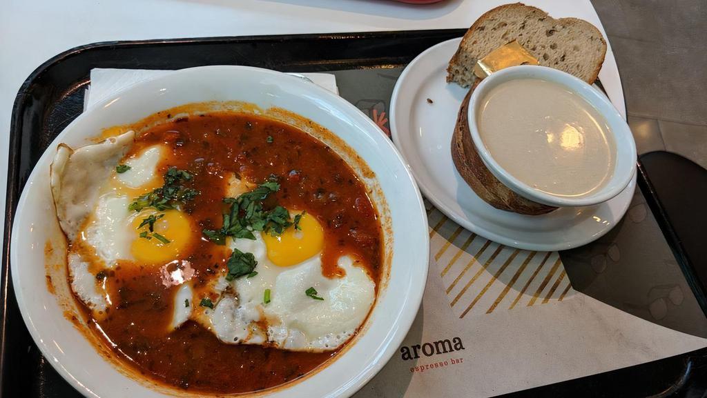Shakshuka · Tomatoes, onions and bell-peppers sauce, topped with two eggs sunny-side up and fresh parsley. Served with tahini sauce and aroma bread and butter.