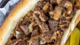 Philly Cheesesteak Sandwich · Thinly shaved ribeye steak grilled with sautéed onions and peppers, smothered with white que...