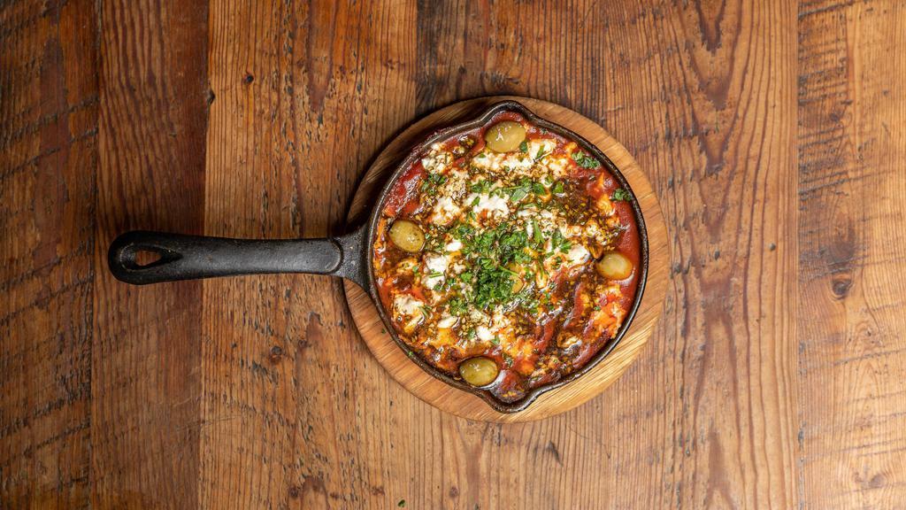 Shakshuka · Gluten-free. Two eggs poached in a spicy tomato sauce. Feta cheese, olives, zaatar, with pita. Add merguez spicy lamb sausage for additional price.