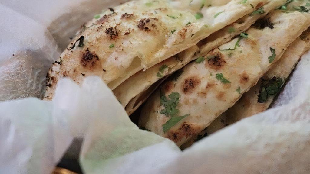 Garlic Naan · Flat and soft bread made of flour, garlic, cilantro, and baked in the clay oven.
