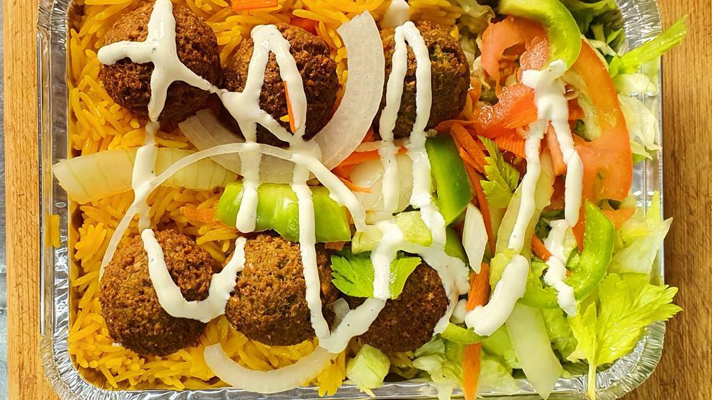 Falafel Over Rice · Smashed falafel over basmati rice with cooked onions, peppers, with side of mix salad.