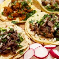 Tacos · topped with onions, cilantro, guacamole, & salsa