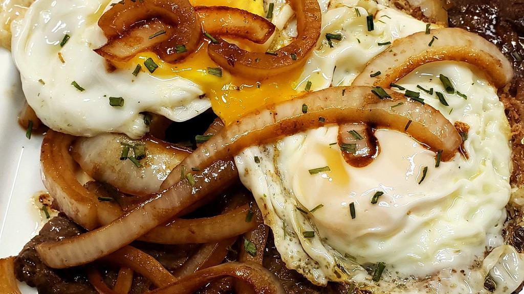 Sirloin Steak & Eggs / Bestec Al Caballo · A mouth-watering sirloin steak and onions topped with two fried eggs.
