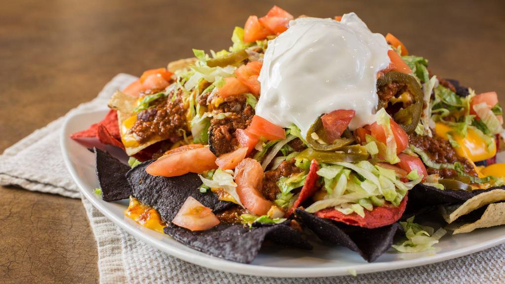 Nachos Supreme · Crispy tortilla chips topped with melted nacho cheese, chili sauce, chopped lettuce, tomatoes, jalapeño peppers, sour cream, and salsa.