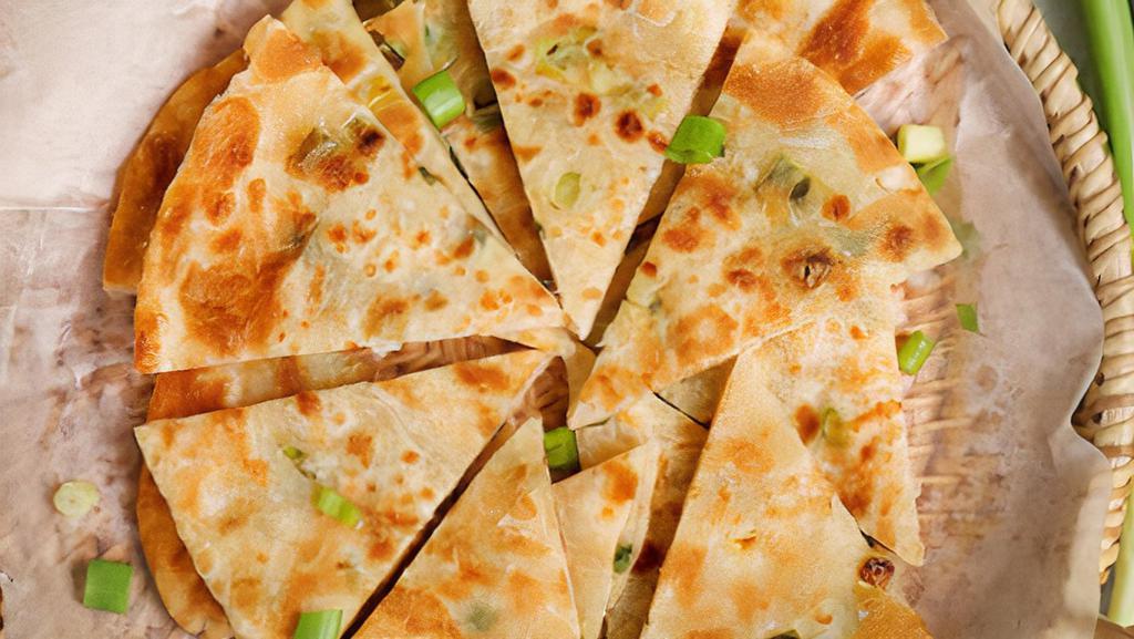 Scallion Pancake · Scallion pancake, is a chinese, savory, unleavened flatbread folded with oil and minced scallions. Unlike western pancakes, it is made from dough instead of batter. It is pan-fried which gives it crisp edges yet also a chewy texture.