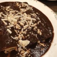 Enchiladas De Mole · Corn fortillas filled with chicken, and topped with mole sauce and cheese, served with rice ...