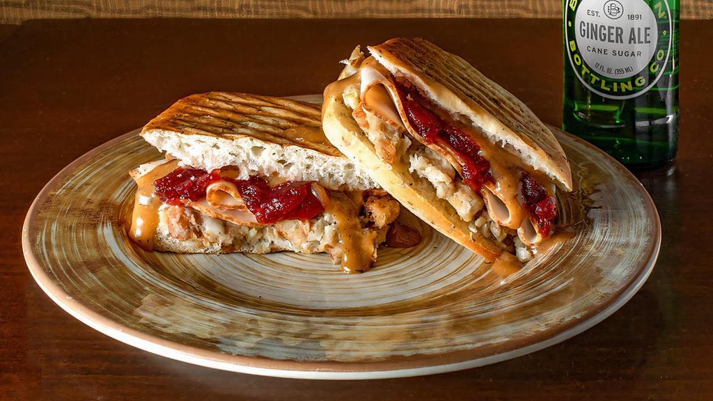 Thanksgiving Panini · Roasted turkey breast, herb stuffing, gravy & cranberry sauce on herb focaccia. Served with choice of side.