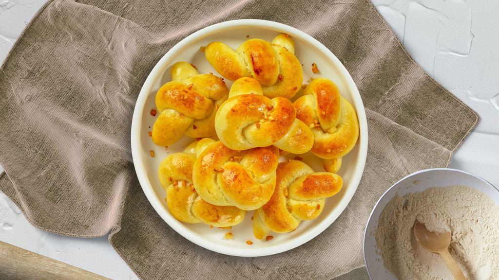 She Loves Me Knot · A classic Italian pizzeria snack, garlic knots are strips of pizza dough tied in a knot, baked and then topped with melted butter, garlic and parsley.
