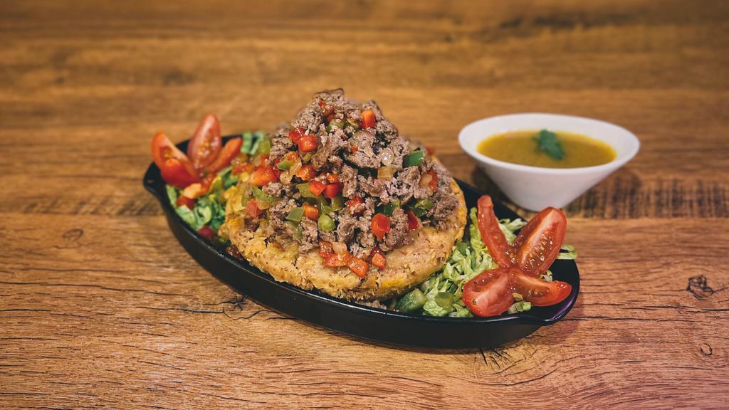 Mofongo De Res · Fried green plantains mashed together in a pilón with salt, our homemade broth, garlic & olive oil. Topped with sautéed beef.