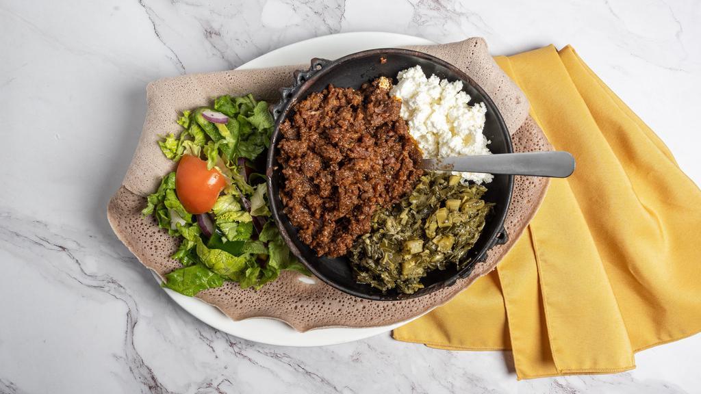 Kitfo · Extra lean cuts of prime beef are finely chopped and soaked in basil, clarified butter, and mitmita. Served with a mashed ethiopian feta cheese and collard greens.