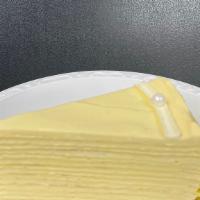 Mango Crêpe Cake · Fourteen layers of crêpes filled with fresh mango cream. Edible pearl for garnish