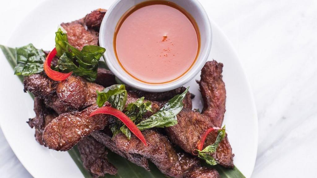 Deep-Fried Pork Strip (Moo Dade Deaw) · This dish includes succulent pork sliced thin and marinated in a sugar and salt brine, then deep fried to a flavorful golden brown. Served with sriracha sauce.