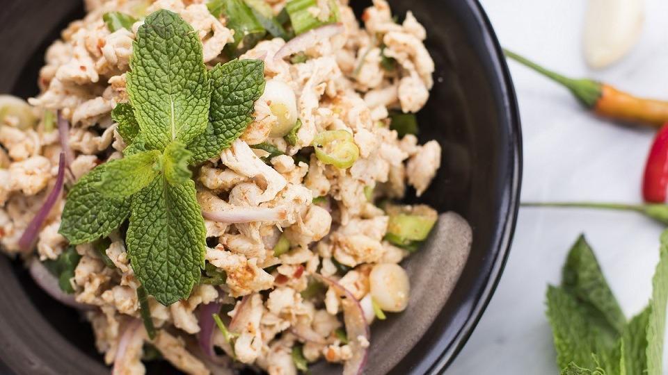 Larb Salad · A flavorful Thai style salad of minced chicken or pork with red onions, spring onions, cilantro, mint leaves, and ground toasted rice tossed in a zesty lime dressing. Served with fresh vegetables.