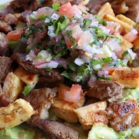 Arepa Frita Mixta · Fried corn flatbread topped with guacamole, grilled steak and chicken, and pico de Gallo