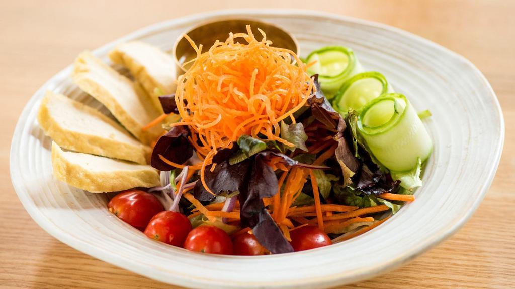 House Salad · Gluten-free. A variety of fresh garden greens with tomatoes, cucumbers, red onions and fried tofu. Served with your choice of miso ginger or peanut dressing.