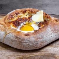Adjaruli · Oven baked boat shaped soft bread filled with farmers cheese, topped with butter and poached...