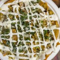 Chilaquiles · Tortilla chips simmered cotija cheese, sour cream, cilantro, and onion in mild green salsa.