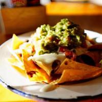 Nachos · Tortilla or tater tots, nacho cheese, black beans, pico di gallo, jalapeño, crema, cilantro.