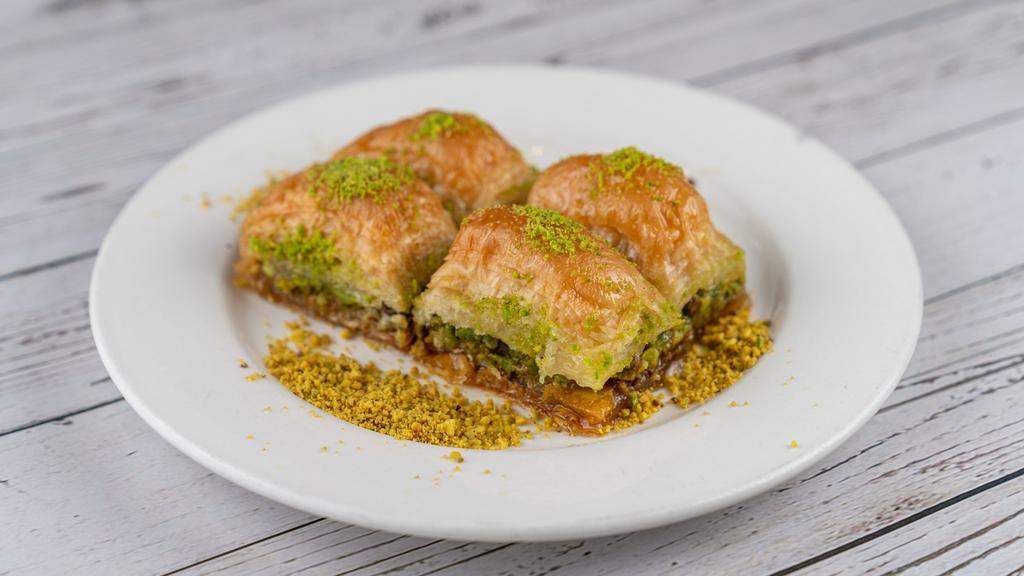 Baklava · Baked thin layered pastry filled with roasted chopped walnuts, flavored with honey syrup and topped with pistachios.