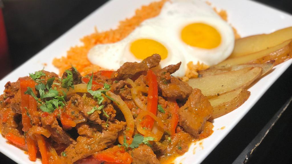 Lomito Saltado · Sirloin strips sauteed with onions, red peppers, and cilantro. Potatoes, yellow rice, and fried eggs.
