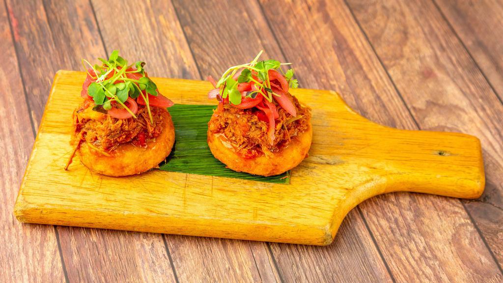 Arepitas Cubanas · Crispy yellow corn cakes topped with pull pork fricassee and pickled onions.