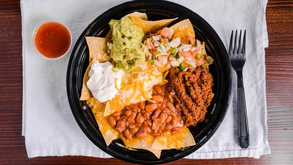 Nachos Supreme · Choice of meat, regular chips, topped with refried beans, black olives, pico de gallo, and nacho cheese. Served with two ounces. Guacamole, sour cream, and salsa on the side.