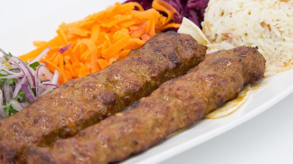 Lamb Adana Kebab · A mouth-watering creation of freshly hand chopped lamb flavored with red bell peppers, light hot peppers, slightly seasoned then expertly char-grilled. Served with jasmine rice, pickled red cabbage, shreded carrots and sliced onions