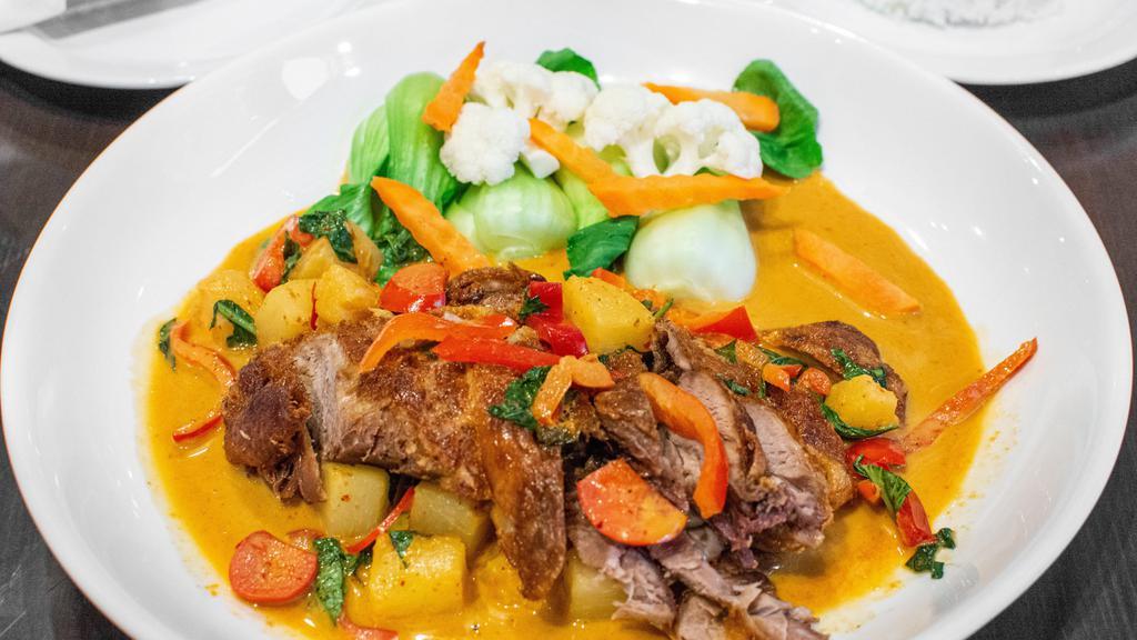 Duck Panang · Mild. Crispy half duck served with panang curry, pineapple, bell pepper, and Thai basil leaves.