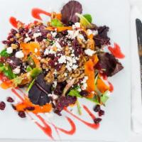 Tuscan Bistro · Field greens tossed with candied walnuts, dried cranberries, creamy goat cheese with a raspb...