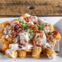 Poutine Tater Tots · Topped with cheese curds, mozzarella, scallions & cracked black peppercorn sauce.