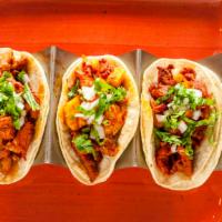 Tacos Al Pastor · Corn tortillas with al pastor pork and pineapple chunks, topped with cilantro and onions.