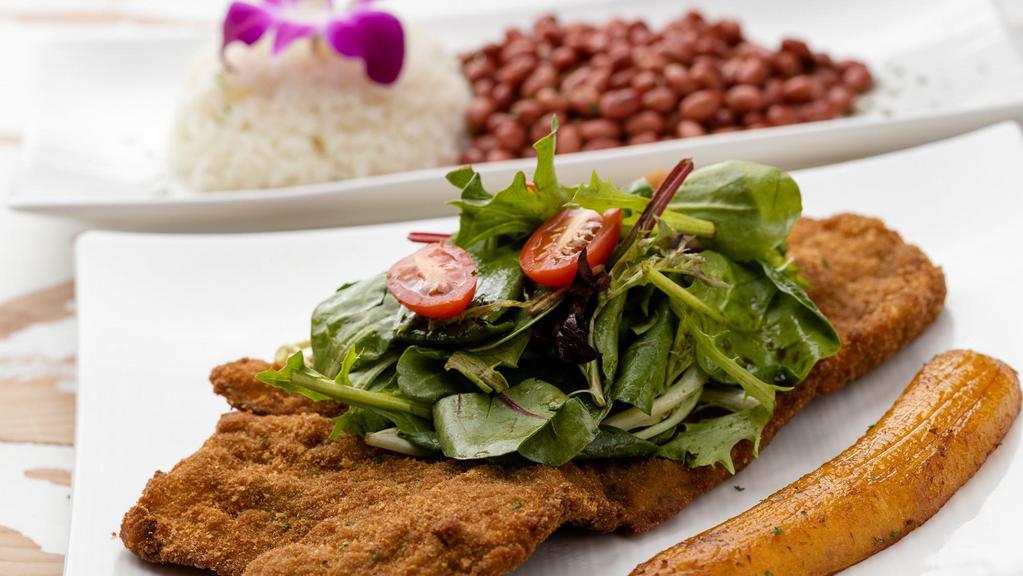 Chuleta De Cerdo · Savory seasoned pork chop breaded and fried served with house salad, white rice and red beans.