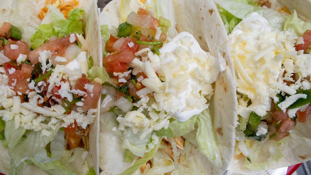 Baja Tacos · Three shredded chicken or ground beef soft flour tacos with lettuce, pico de gallo, sour cream and shredded cheese. Served with Mexican rice and refried beans. * 
 
*House Favorite.
