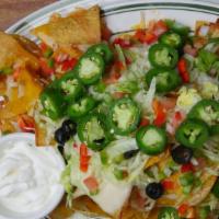 Nachos Supreme · Corn tortilla chips topped with melted Cheddar and Monterey Jack, black olives, tomatoes, on...