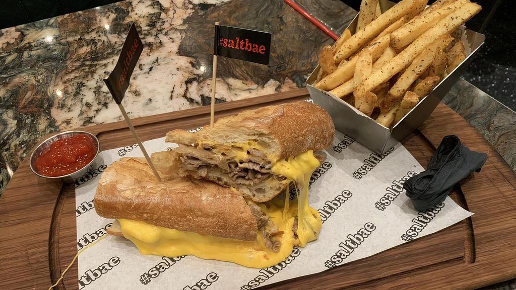 Steak Sandwich · Home baked baguette, thinly sliced strip loin sauteed with caramelized onion, topped with melted cheddar cheese and served with french fries.