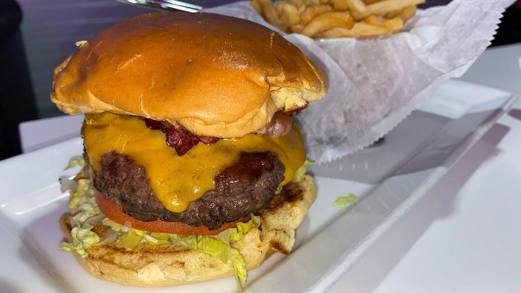 Bacon Cheddar Burger · 9oz 100% beef patty, bacon, cheddar cheese, lettuce, tomato & mayo/ketchup sauce on a toasted brioche bun. Choice of skinny or seasoned curly fries. All burgers are cooked well done unless specified.
