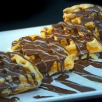 Nutella Waffle · Golden belgian waffle topped with a Nutella drizzle and served with a side of maple syrup.