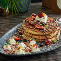 Fruity Pebble Pancakes · fruity pebbles cereal, raspberry,
white chocolate drizzle
