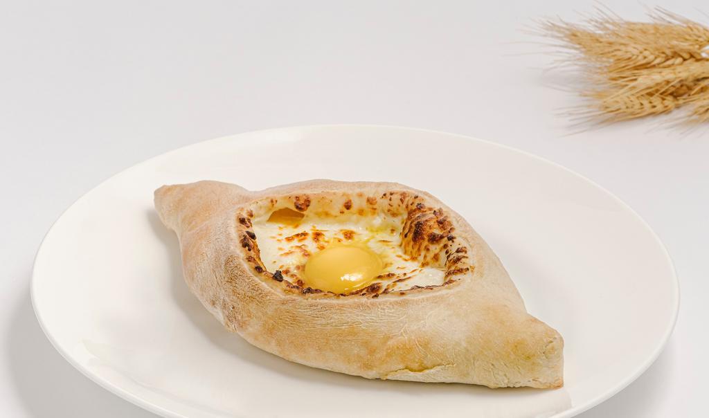 Adjaruli Khachapuri  · Boat shaped oven baked dough stuffed with molten cheese, topped with egg & a choice of a butter. Vegetarian.