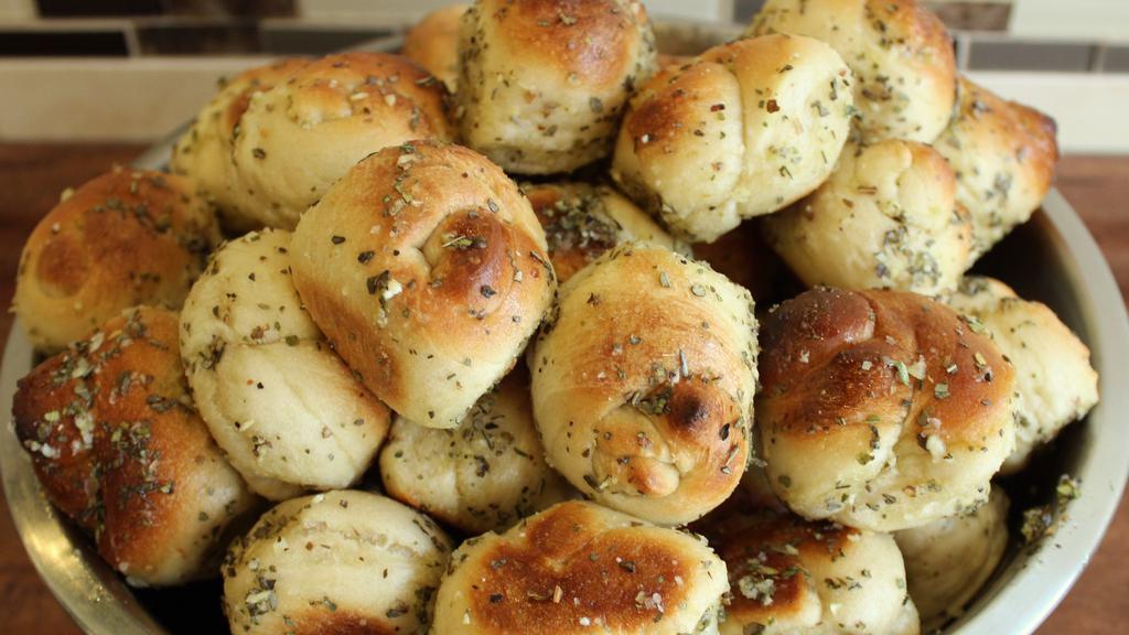 Garlic Knots · A classic snack, our garlic knots are strips of pizza dough tied in a knot, baked, and then topped with melted butter, garlic, and parsley. Four pieces.