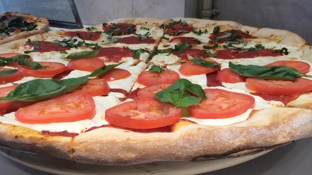 Caprese Pizza · Topped with classic cheese, pesto, tomatoes, red onions, and fresh basil.