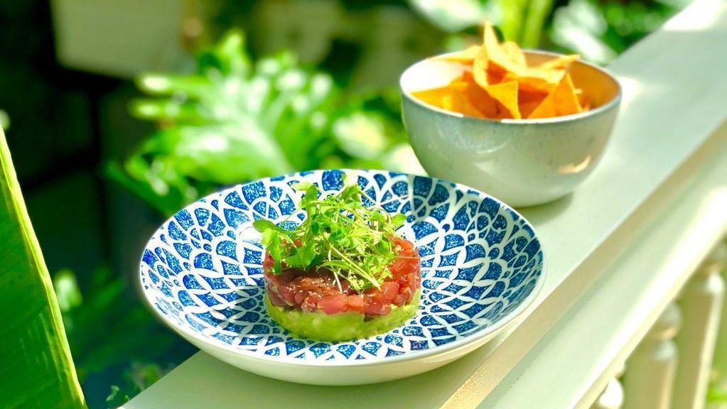 Tuna Tartare · A beautiful section of tuna loin that is large diced, uniformly, lathered with a soy sauce made with chinese 5-spice, garlic and ginger, and scallions, set over a ring of fresh guacamole. Served with house made corn tortilla chips.